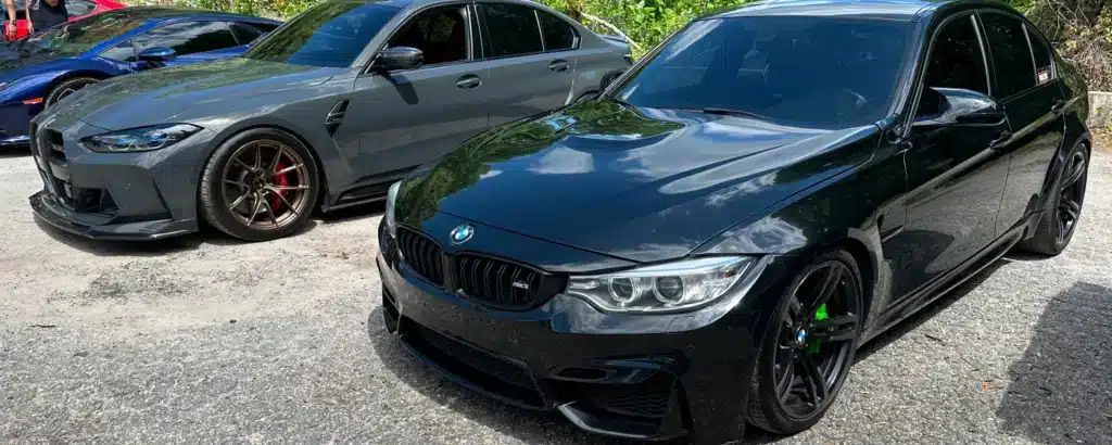 BMW Repair & Service in Gainesville, GA with Atlanta Speedwerks. Two parked BMW cars, a black one in the foreground and a gray one behind it, both on a sunny day.