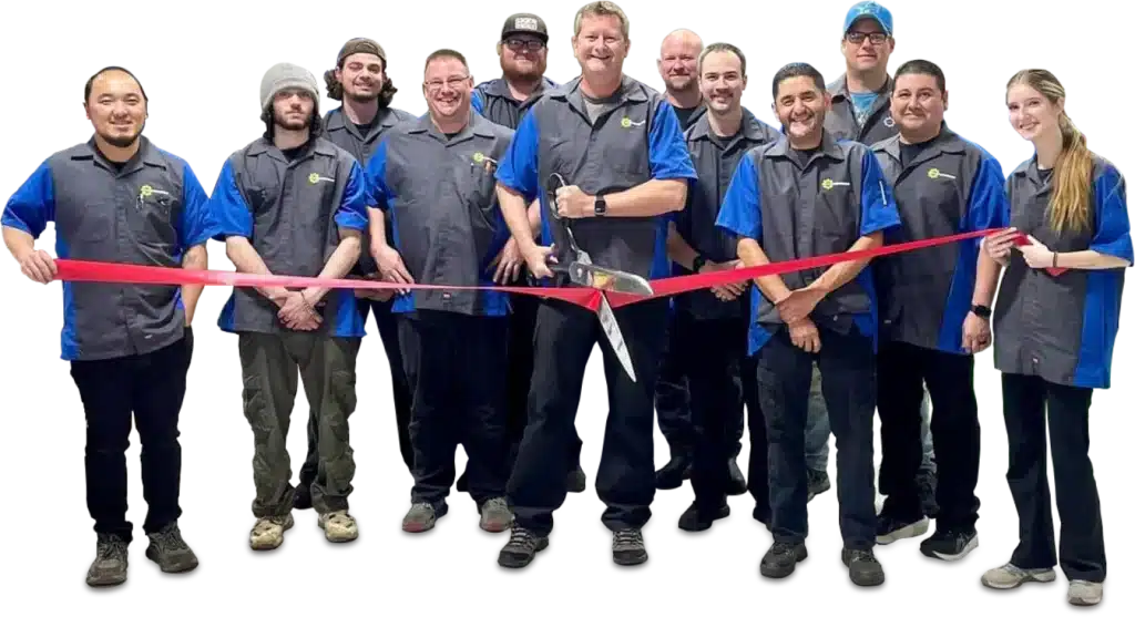 A group of people in matching blue uniforms holding a red ribbon, with one person in the center holding oversized scissors.