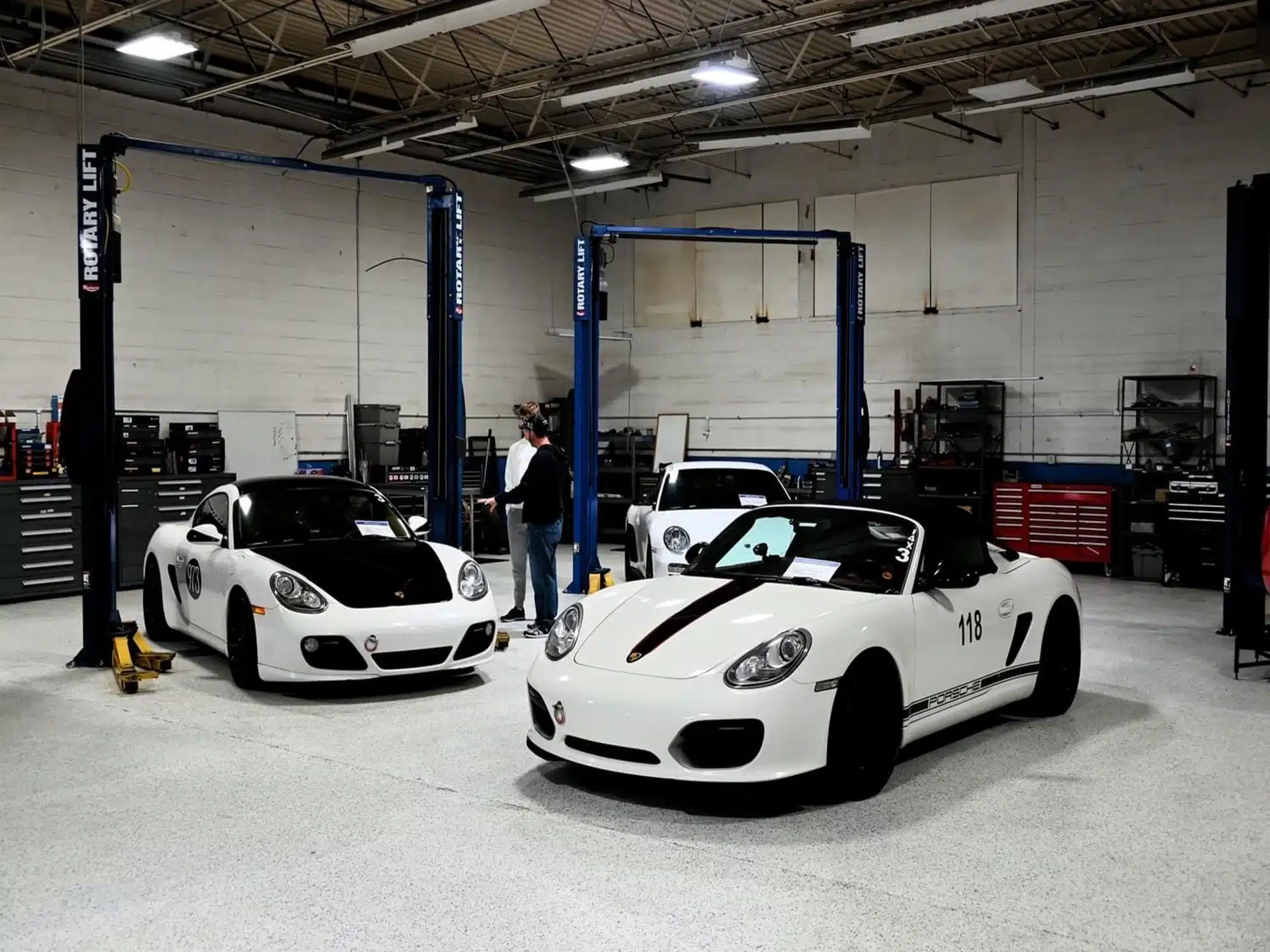 German car care at Atlanta Speedwerks in Gainesville, GA: High-quality maintenance and repair for your German vehicle, ensuring optimal performance and longevity. Image shows a well-equipped workshop with several white Porsche cars under service.