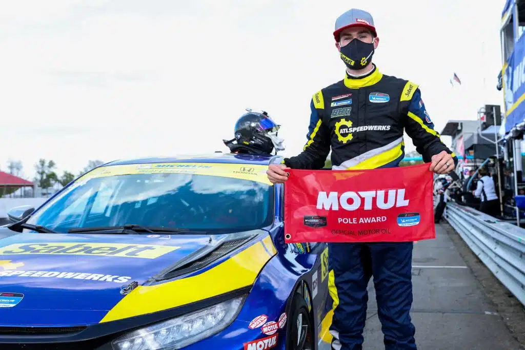 a man holding a red sign next to a race car