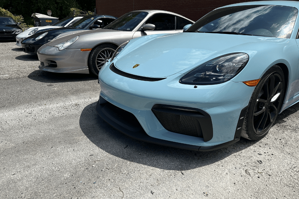 european car brands, european auto repair in Gainesville, GA at Atlanta Speedwerks. Light blue Porsche Cayman GT4 parked among other Porsche sports cars.