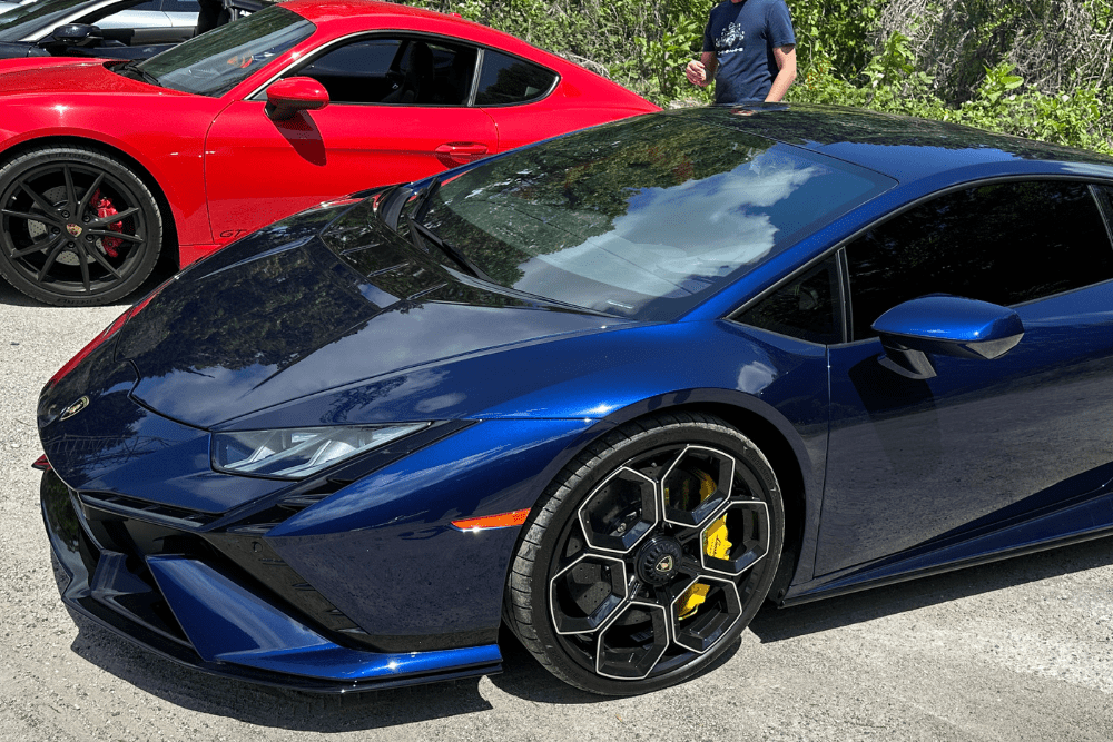 Lamborghini Repair in Gainesville, GA by Atlanta Speedwerks. An image of a blue Lamborghini Huracán with yellow brake calipers is parked next to a red Porsche Cayman GT4, highlighting high-performance vehicles.