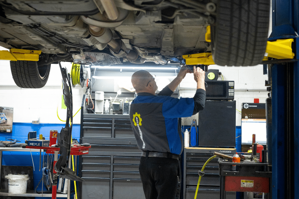 Car problems, auto repair in Gainesville, GA by Atlanta Speedwerks. Image of a technician inspecting a vehicle’s undercarriage on a lift during professional suspension, exhaust, and drivetrain service.