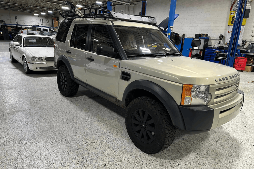 European auto repair near Lake Lanier, GA at Atlanta Speedwerks. Image of a Land Rover SUV inside the service shop with another vehicle parked behind it, highlighting European vehicle maintenance.