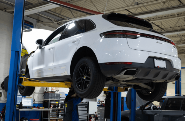 Car issues, European auto repair in Gainesville, GA, at Atlanta Speedwerks. Image shows a luxury Porsche SUV on a lift while technicians perform professional diagnostics and service.