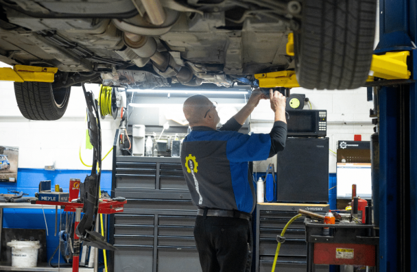 Car problems, auto repair in Gainesville, GA by Atlanta Speedwerks. Image of a technician inspecting a vehicle’s undercarriage on a lift during professional suspension, exhaust, and drivetrain service.