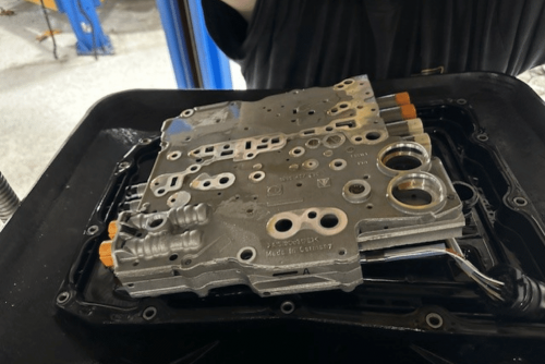 Image of a disassembled Porsche PDK valve body on a workbench, showcasing the shop’s precision in transmission service to ensure performance, reliability, and safe driving.