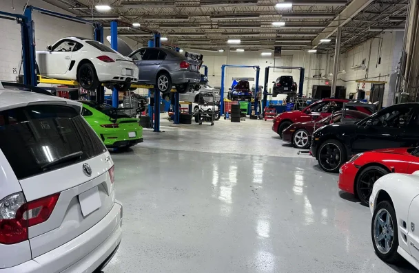 A spacious auto repair shop with several cars of different colors on lifts and parked on the floor.