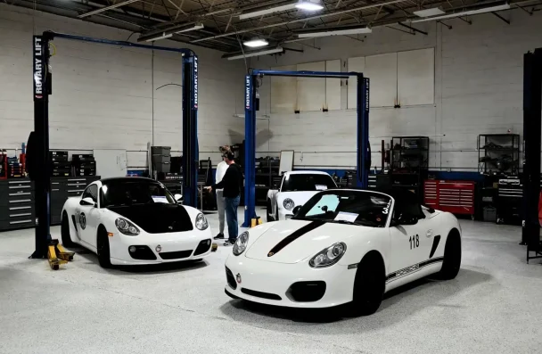 German car care at Atlanta Speedwerks in Gainesville, GA: High-quality maintenance and repair for your German vehicle, ensuring optimal performance and longevity. Image shows a well-equipped workshop with several white Porsche cars under service.