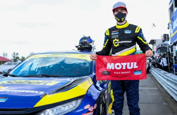 a man holding a red sign next to a race car